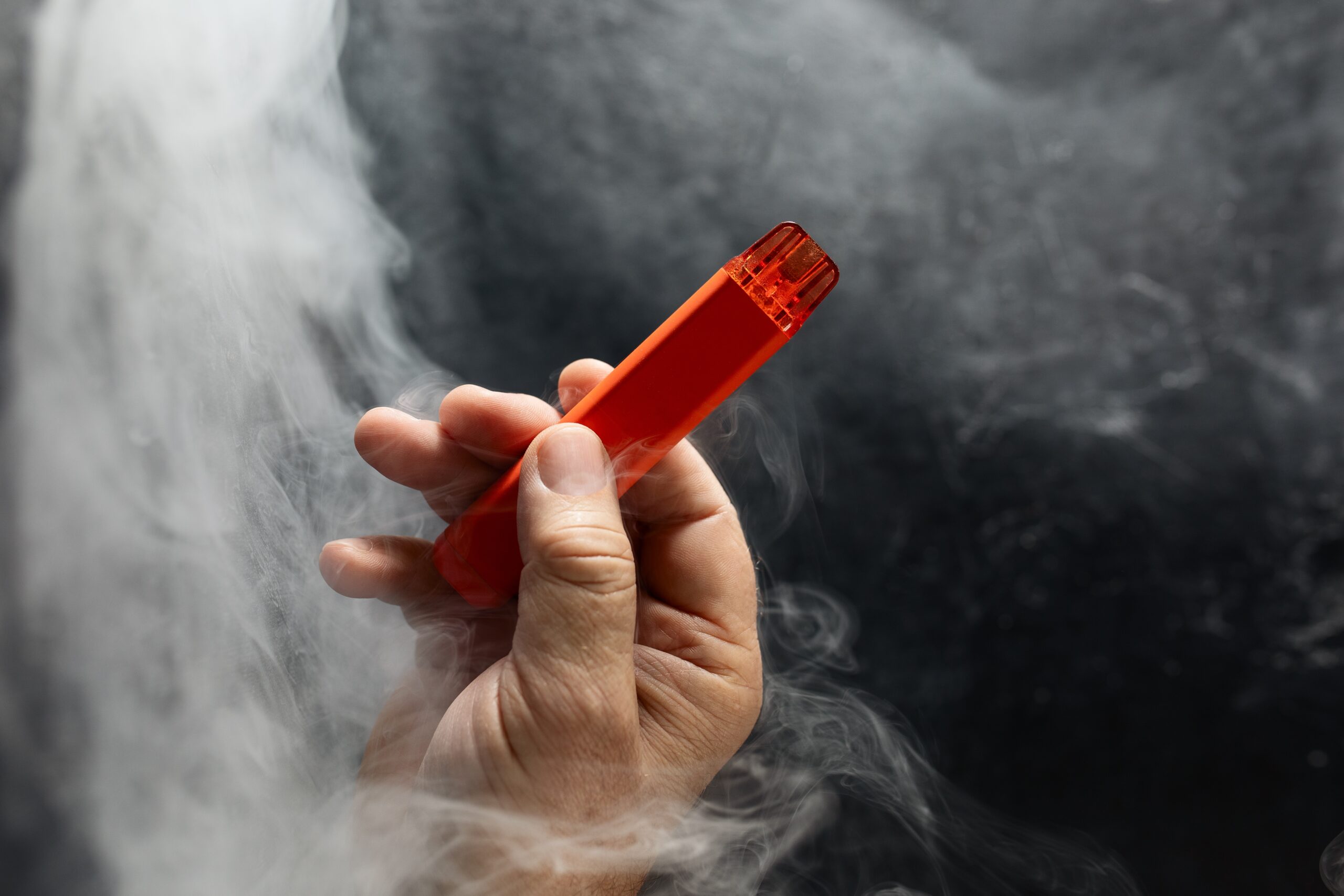 Hand holding an orange vape pen